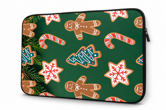 A laptop sleeve featuring a festive Christmas pattern with gingerbread cookies, candy canes, snowflakes, and pine branches on a dark green background, shown against a plain white background.
