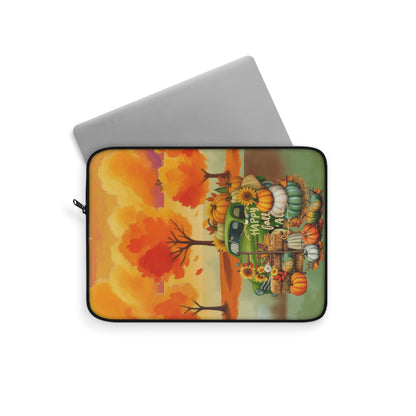 A laptop sleeve featuring a colorful autumn harvest illustration with pumpkins, gourds, sunflowers, and an orange tree, shown on a white background with a silver laptop partially inserted.