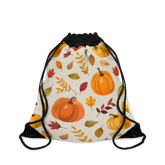 A drawstring backpack with a black cord closure and a cream-colored body, decorated with an autumn pattern of orange pumpkins and colorful leaves in shades of red, yellow, and green.