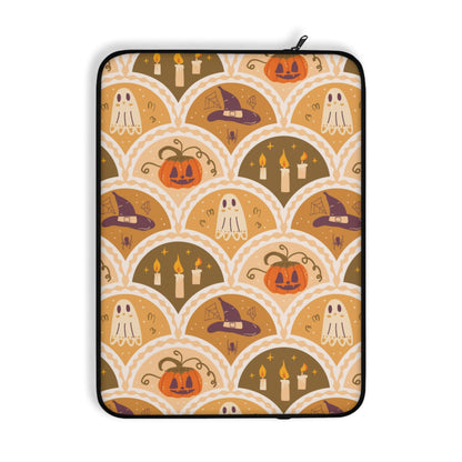 A laptop sleeve featuring a repeating Halloween-themed pattern with pumpkins, ghosts, witch hats, and candles in warm autumn colors on a white background.