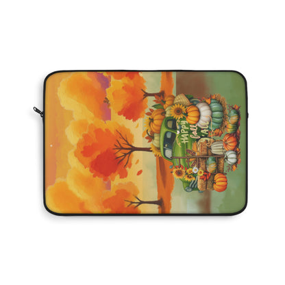 A laptop sleeve featuring a colorful autumn-themed illustration with orange and red trees, pumpkins, gourds, and a green truck carrying fall harvest items. The text 'We'll all fall in love' is printed on the side of the truck.