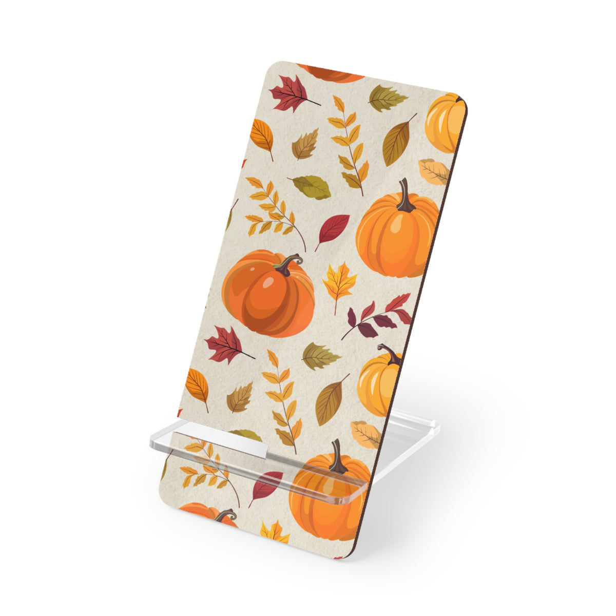 A phone stand with a fall autumn pattern featuring pumpkins and leaves on a cream background, supported by a clear acrylic base on a white studio background.