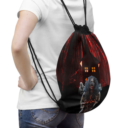 A person wearing a white t-shirt and blue jeans carries a black drawstring backpack with a spooky Halloween graphic of a haunted house and a zombie.