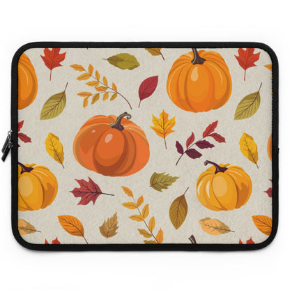 A laptop sleeve featuring a repeating autumn pattern of orange pumpkins and colorful fall leaves on a light beige background, finished with a black zipper and black trim.