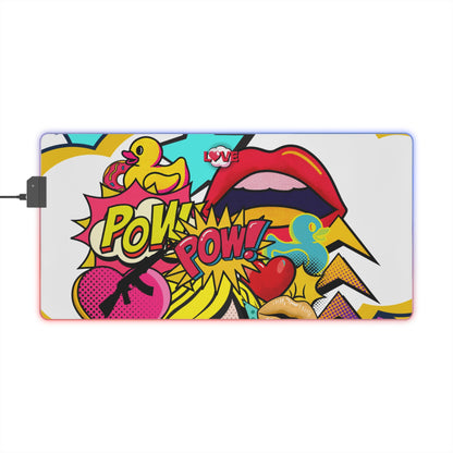 A rectangular desk mat with a colorful pop-art comic book design featuring a yellow rubber duck, red lips, a pink heart, and 'POW! POW!' text, shown on a white background with a power cable extending from the left.