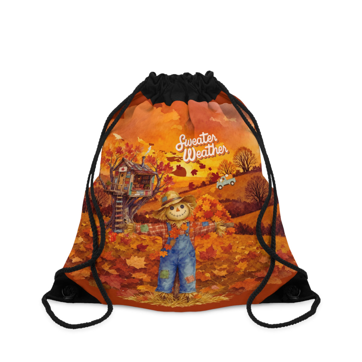 A drawstring backpack with a black top and black cords, featuring a colorful autumn landscape graphic with a scarecrow, treehouse, fall leaves, and the words 'Sweater Weather'.
