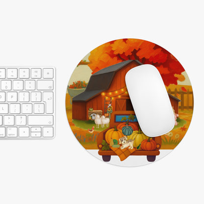 A round MOUSE PAD with a colorful autumn farm illustration, shown next to a white keyboard and mouse on a light gray background. The design features a barn, pumpkins, sheep, and fall foliage.