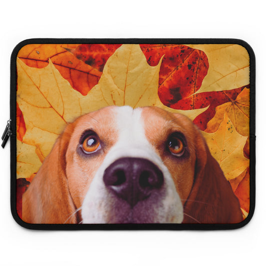 A laptop sleeve featuring a printed design of a beagle dog's face surrounded by colorful autumn leaves in shades of orange, yellow, and red, set against a plain white background.
