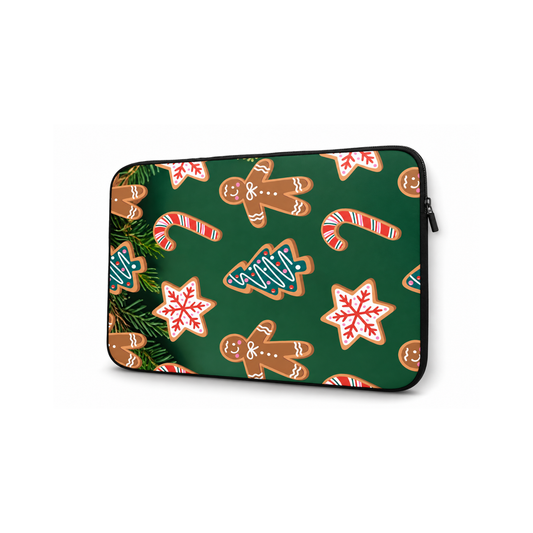 A laptop sleeve featuring a festive Christmas pattern with gingerbread men, candy canes, snowflakes, and pine branches on a dark green background, shown on a plain white background.